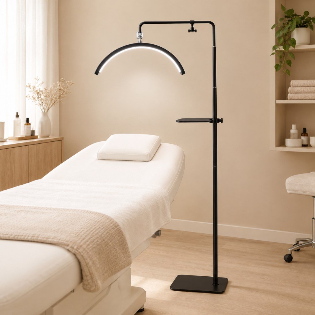 Lampe pour extension de cils : un arc demi-lune au-dessus du divan Lampe demi-lune Pro installée en cabine, l'arc allumé au-dessus de la tête d'un divan de soin