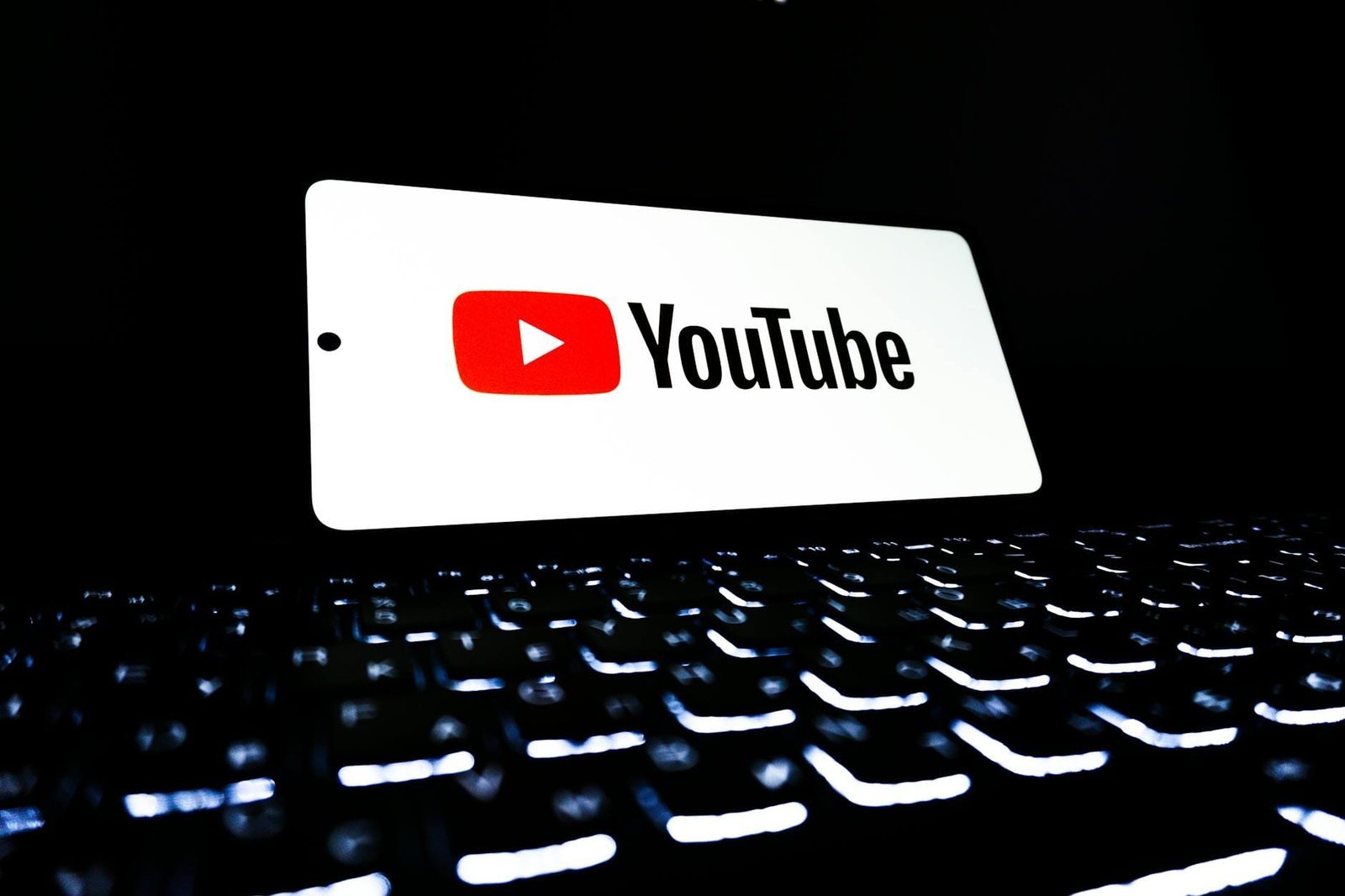 Téléphone affichant le logo YouTube posé sur un clavier rétroéclairé
